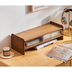 a wooden desk with headphones on top of it next to a lamp and magazine rack