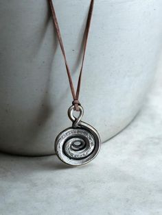 Hand-Forged Spiral Necklace -  Protect Your Spirit with Iron EleganceDiscover the blend of ancient lore and modern craftsmanship with this authentic hand-forged Spiral  necklace. Created using traditional blacksmithing techniques (hammer and anvil), each necklace carries with it a piece of history and the mark of individuality. Key Features: 🛠️  Handcrafted Excellence: Forged by hand for a unique, one-of-a-kind design. ⚒️ Material Integrity: Made with high-quality iron to ensure durability and longevity. 🎨 Aesthetic Appeal: Rustic, timeless design that complements any attire, from casual to formal. Product Details: Pendant Size: Approximately 2 inches in height.Necklace Length: Adjustable leather cord for comfort and versatility. Color: Natural polished iron with a subtle patina for an a Elegant Hand Forged Necklace, Traditional Hand Forged Necklace As Gift, Symbolic Hand Forged Pendant Necklace, Hand Forged Amulet Pendant Jewelry, Bronze Hand Forged Amulet Necklaces, Iron Jewelry, Blacksmith Forge, Spiral Necklace, Amulet Necklace