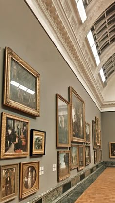 a room filled with lots of paintings and framed pictures on the wall next to a wooden table