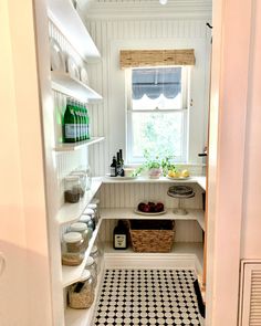 a kitchen with black and white tile flooring next to an open door leading to a window