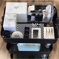 a black container filled with lots of white dishes and utensils on top of a wooden floor