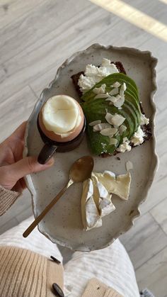 a person holding a plate with food on it and spoons in front of them