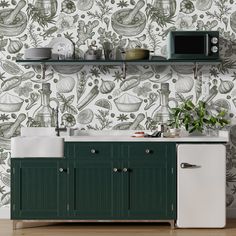 a kitchen with green cabinets and wallpaper that has an image of plants on it