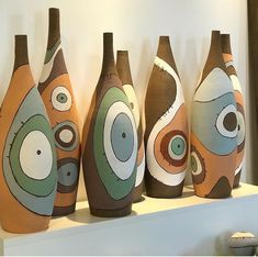 five vases with different designs on them sitting on a shelf