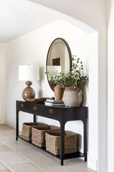 a black console table with baskets under a mirror