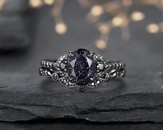 a fancy ring with an oval shaped purple diamond in the center on top of a rock