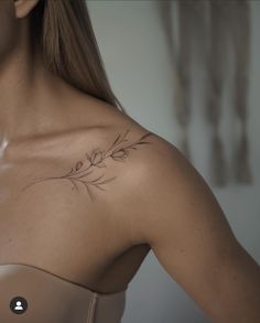 a woman with a tattoo on her chest and shoulder is looking down at the camera