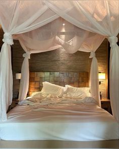 a bed with white drapes and pillows on it's headboard is shown