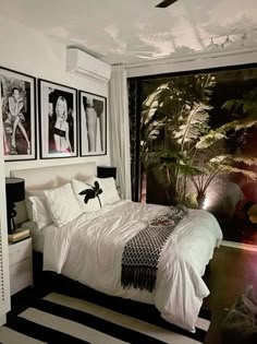 a bedroom with pictures on the wall above the bed and below the bed is a black and white striped rug