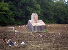 people are sitting in the mud near a barn