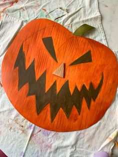 an orange carved pumpkin sitting on top of a white piece of paper next to scissors