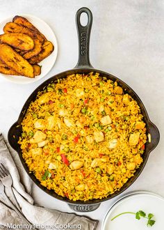 a skillet filled with chicken and rice next to two bowls