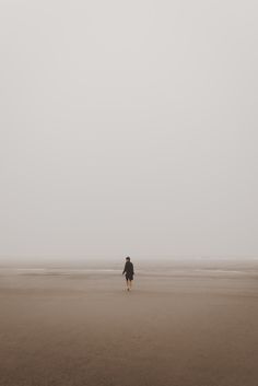 a person walking on the beach with a kite flying in the sky above them,