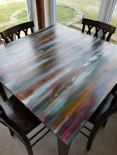 a wooden table with chairs around it in front of a window