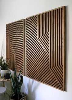 two wooden panels mounted to the side of a wall next to a potted plant