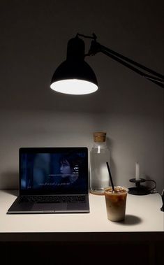 a laptop computer sitting on top of a desk next to a cup of coffee and a lamp