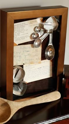 spoons and measuring spoons are in a shadow box with writing on the side