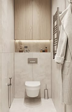 a white toilet sitting in a bathroom next to a towel rack and wooden cabinet above it