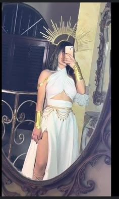 a woman in a white dress taking a selfie with her cell phone and wearing gold jewelry