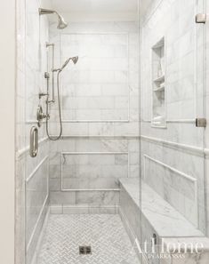 a walk in shower sitting next to a white tiled wall and floor with glass doors