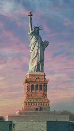 the statue of liberty in new york city, ny at sunset with pink and blue sky