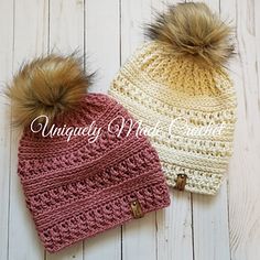 two crocheted hats with pom - poms on them