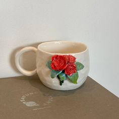 a white coffee cup with red roses painted on it