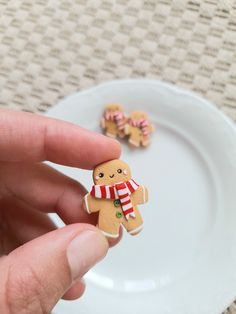 a hand holding a tiny gingerbread man on a plate