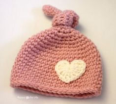 a crocheted pink hat with a white heart on it