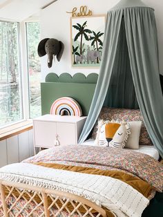 a bed with a canopy over it in a bedroom next to a window and an elephant head on the wall