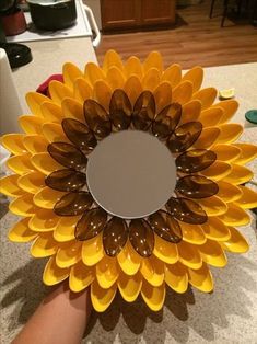 a sunflower shaped mirror sitting on top of a counter next to a person's hand