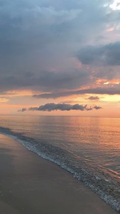 the sun is setting over the ocean with clouds in the sky and water on the beach