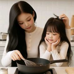 two girls are cooking in a wok on the stove