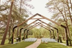 an outdoor wedding venue set up with white chairs and wooden structures, surrounded by trees