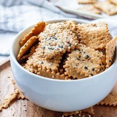 some crackers are in a white bowl on a wooden table