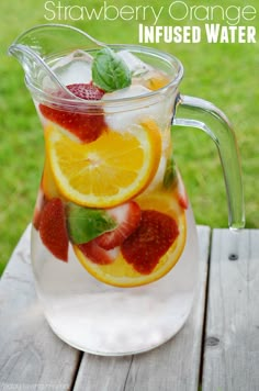 a pitcher filled with fruit sitting on top of a table