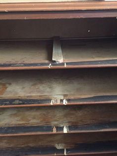 the bottom part of an old wooden shelf with metal bars on it and rusted paint