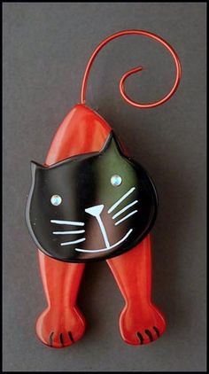 an orange and black cat brooch sitting on top of a gray table next to a red string