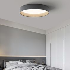 a large bed sitting under a round light in a bedroom next to a white wall