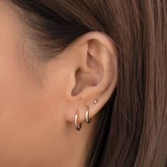 a close up view of a woman's ear with two small hoops on it