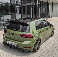 a green vw golf gtr parked in front of a building on the street