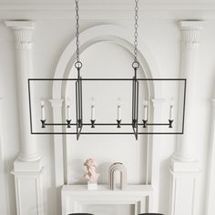 a chandelier hanging from the ceiling in a room with white walls and black chairs