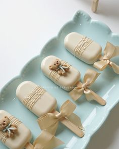 baby shower favors are arranged on a blue tray with gold bows and teddy bears in them