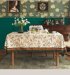 a dining room with green walls and floral wallpaper, including a white table cloth