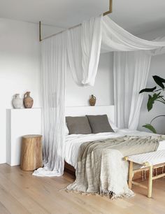 a bed with white drapes hanging over it's head