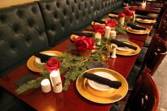 the table is set with gold plates and black napkins, red roses on them