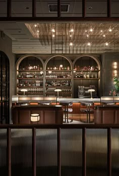 an empty bar with lots of bottles on the shelves and lights hanging from the ceiling