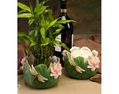 two vases with plants and candles on a table next to a bottle of wine