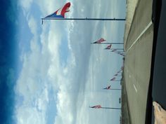 several american flags are flying in the wind on an empty highway with blue skies and white clouds