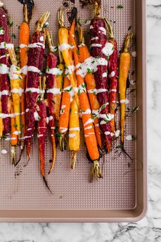 roasted carrots with white sauce and herbs on a baking sheet, ready to be cooked